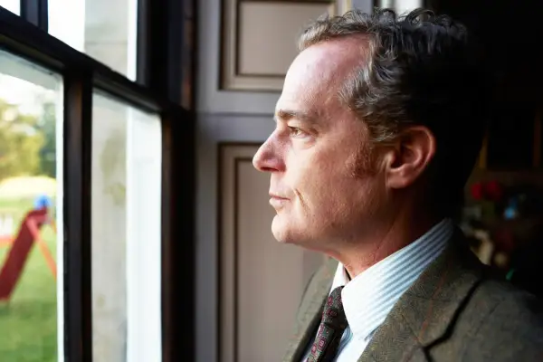 Bernard De Floures (ADAM JAMES) Bernard looks out on the Fete. A side profile looking out of a window