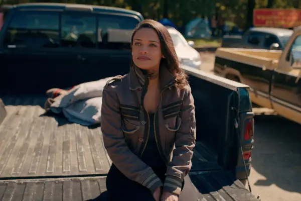 Kandyse McClure as Kaia Bryant at on the back of a truck wearing a leather jacket, smiling.