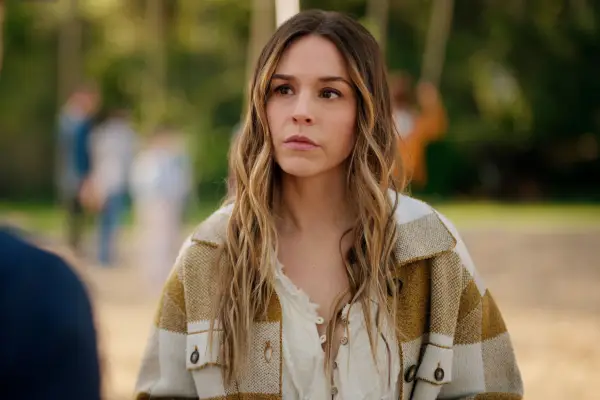Elise Gatien as Lark wearing a white blouse, looking concerned.