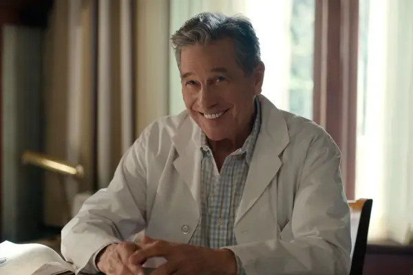 Tim Matheson as Doc, smiling ahead as he wears a doctor