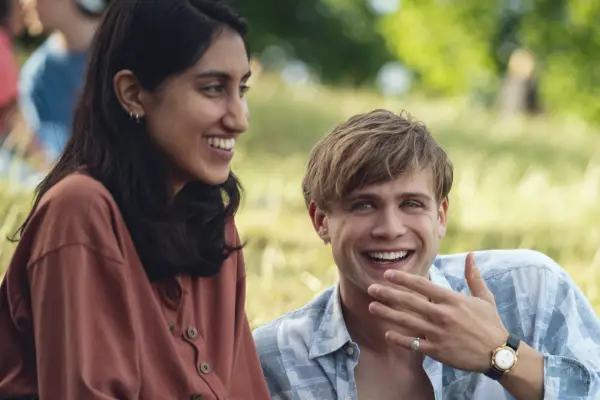 Ambika Mod as Emma & Leo Woodall as Dexter in One Day lying together in a field laughing