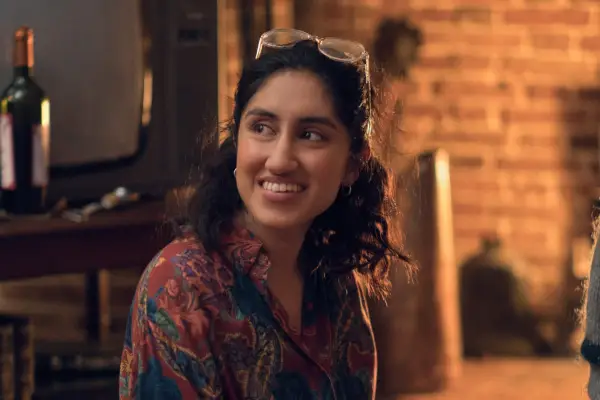 Ambika Mod as Emma, sat on the floor by a fireplace in One Day