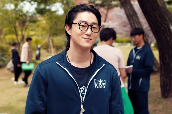 Peter Thurnwald as Alex Finnerty, standing outside wearing glasses and a sweater