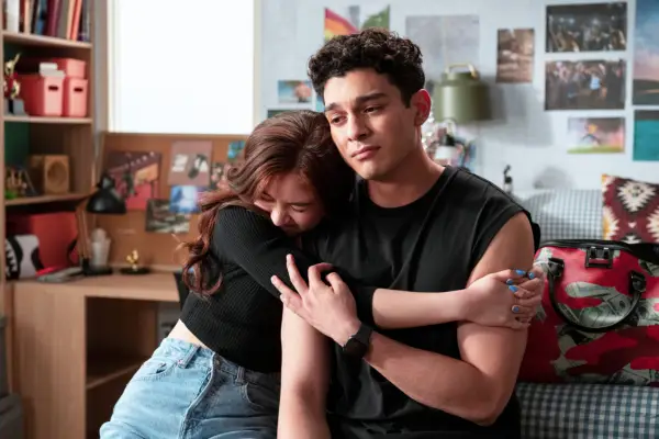 Anna Cathcart as Kitty Song Covey sat on a bed next to Anthony Keyvan as Q with her arms wrapped around him