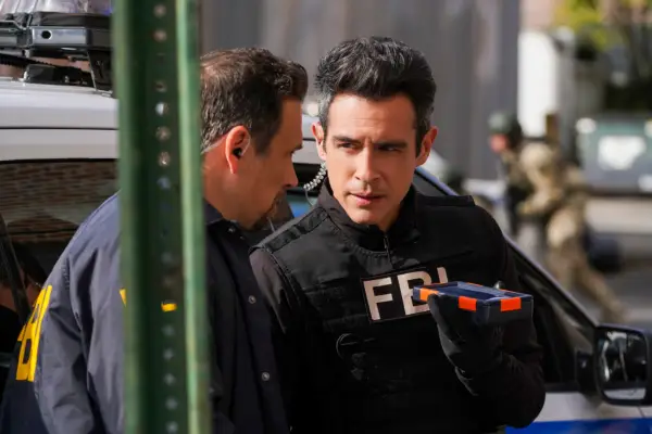 Two FBI agents lean in to talk to each other, looking as if they could be discussing sensitive information