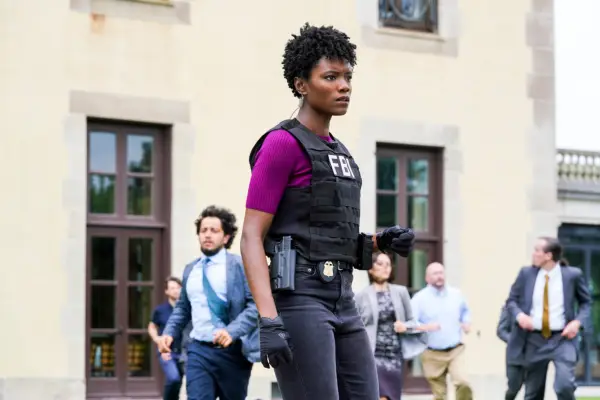 An FBI agent wearing a bulletproof vest stands alert, ready for action