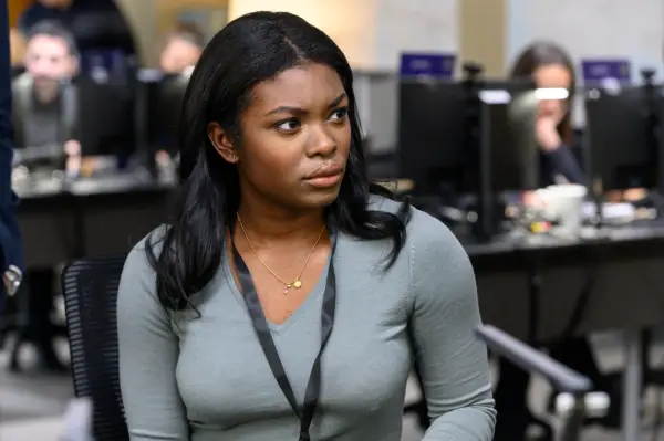 A woman wearing a lanyard in an office environment casts a concerned glance to her left-hand side