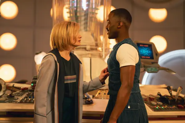 Jodie Whittaker as the Doctor and Ncuti Gatwa as the Doctor standing in the TARDIS and looking at each other, with Thirteen
