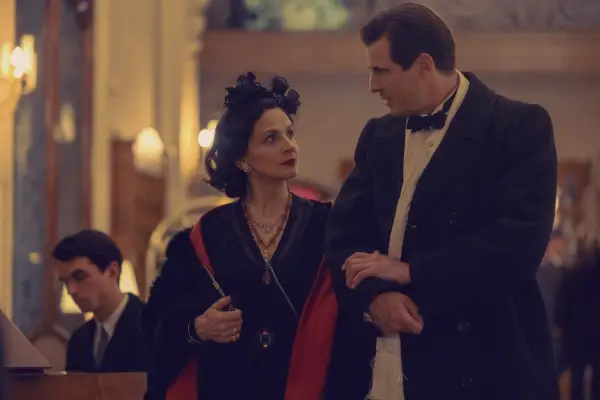 Juliette Binoche as Coco Chanel and Claes Bang as Spatz in The New Look walking with their arms linked.