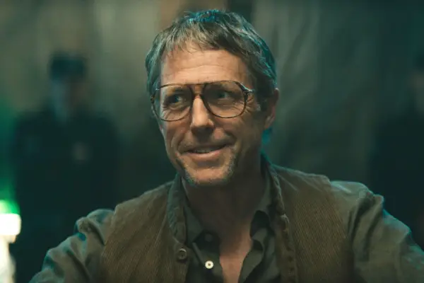Hugh Grant as the Leader of the Opposition, wearing big glasses and with an uneasy smile in The Regime