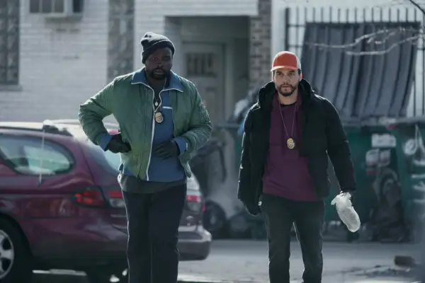 Brian Tyree Henry and Wagner Moura in Dope Thief, wearing police badges and walking together