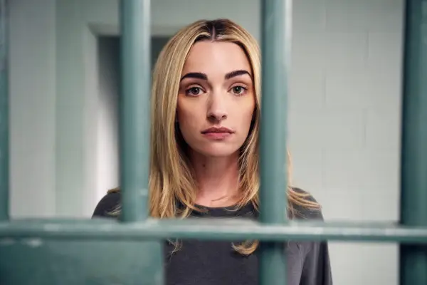 Brianne Howey as Georgia, standing in a prison cell behind bars