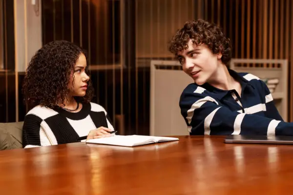 Antonia Gentry as Ginny and Ty Doran as Wolfe sat next to one another at a desk. They