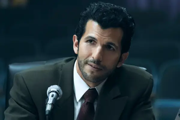 Raul Diaz wearing a suit, sat at a desk, with a microphone in front of him