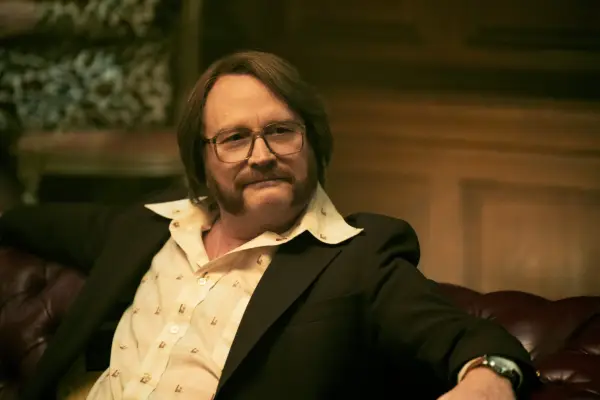 Arturo wearing a white shirt and black jacket, sat down, with one arm propped up on the back of the chair