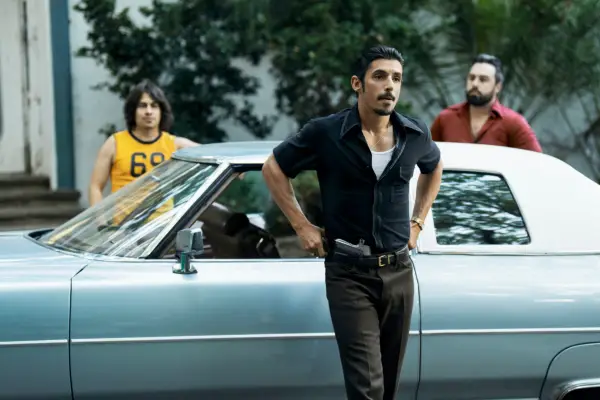 Dario dressed in a black shirt and trousers, stood in front of his car with his hands on his hips