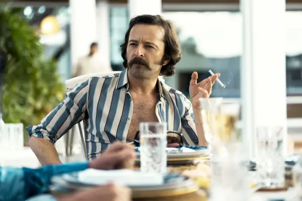 Rafa sat at a dining table outside, talking to people, with a cigarette in his hand. He