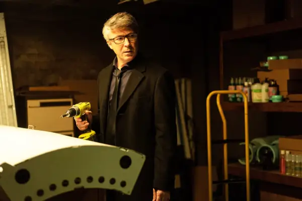 Aidan Gillen as Frank Kinsella, standing in a garage holding a drill