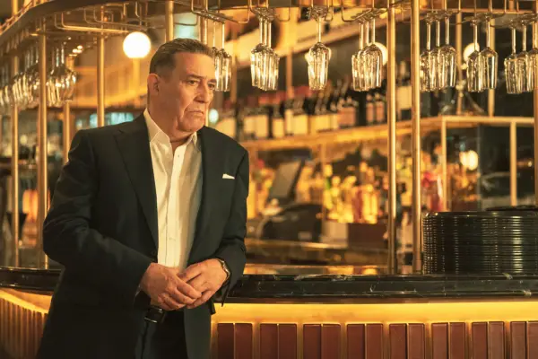 Ciarán Hinds as Eamon Cunningham, leaning against a bar
