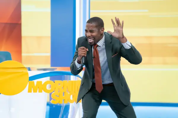 Daniel with a microphone in hand singing in the morning show studio