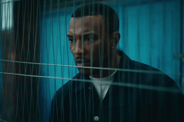 Ashley Walters as Dushane standing behind a fence in Top Boy season 5.