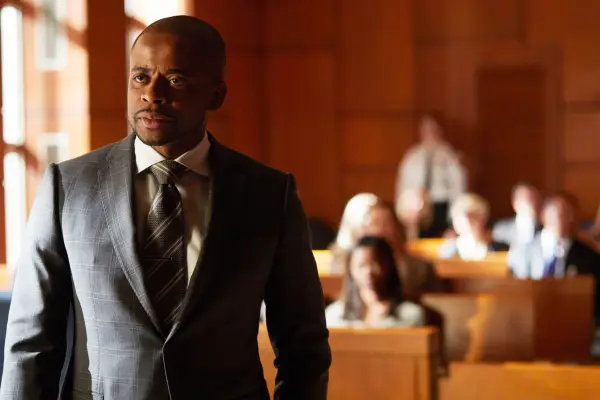 Dulé Hill as Alex Williams in Suits, stood in a courtroom and wearing a suit