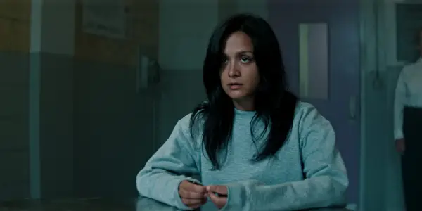 Amy-Leigh Hickman as Nadia Farran sat in a prison in a grey jumper in You season 5.