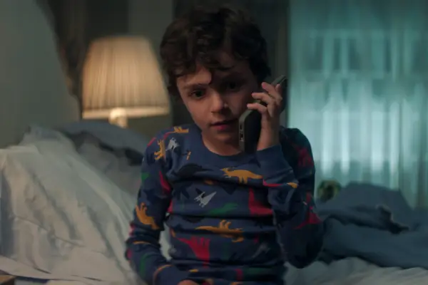 Frankie Demaio as Henry Goldberg in You season 5 on the phone to someone as he sits on the edge of his bed in his pyjamas.