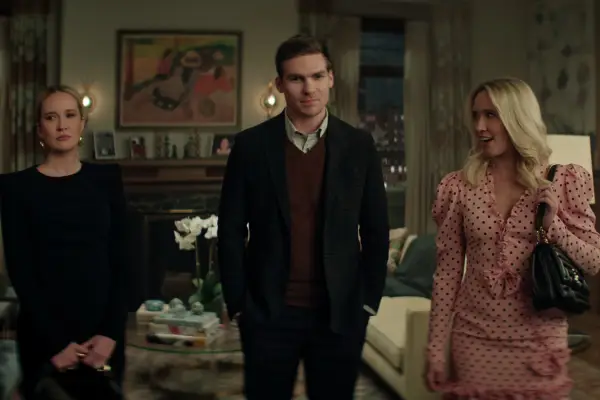 Anna Camp as Reagan Lockwood, Pete Ploszek as Harrison, Anna Camp as Maddie Lockwood in You all standing in a living room, with pained smiles and wearing formal attire.