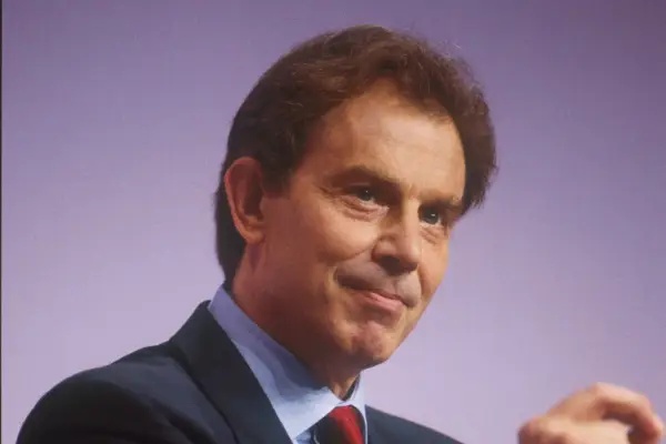 Tony Blair in a suit in front of a purple background