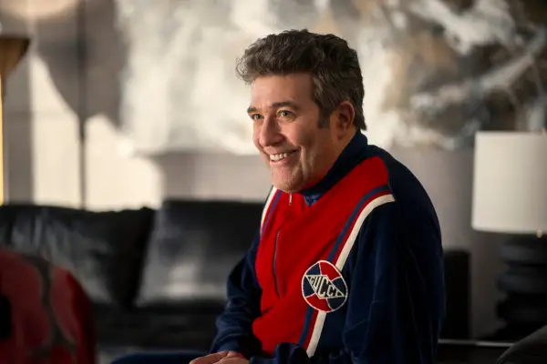 Mick wearing a tracksuit and sat in his office with a smile on his face