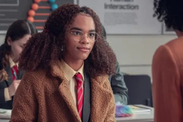 Isaac stood in a bookshop smiling holding a pile of books