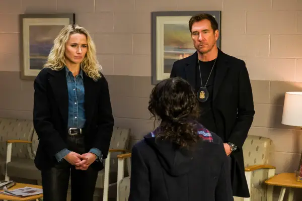 Shantel VanSanten and Dylan McDermott wearing black jackets and facing a person with their back turned to the camera.