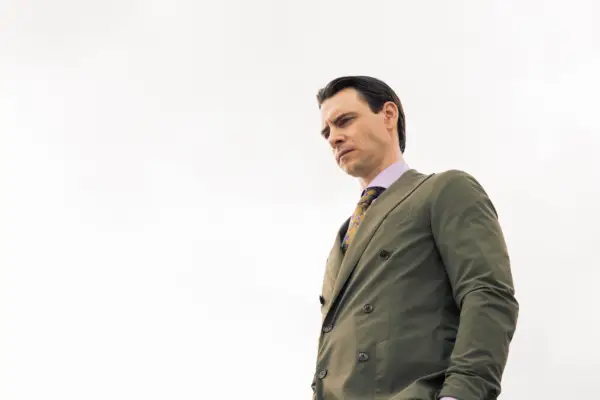 Harry Lloyd in The Iris Affair, wearing a suit.