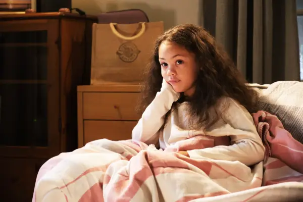 Bella Rei Blue Stevenson as Rosie, sat on a sofa with a duvet over her