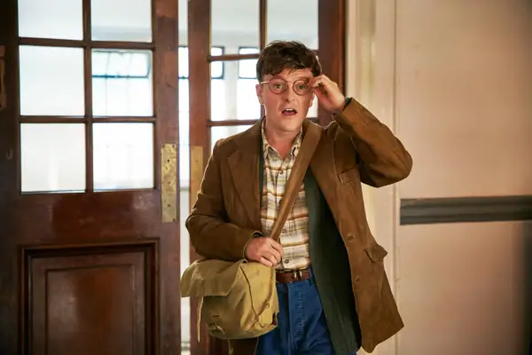 Ian walking into a room, holding a hand to his glasses.