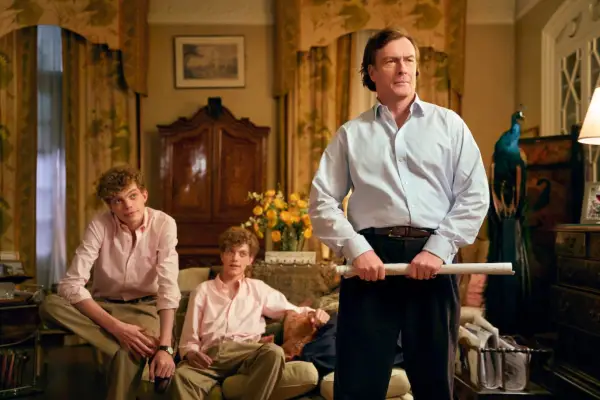 Toby standing in the middle of his living room, with a rolled up magazine in his hand