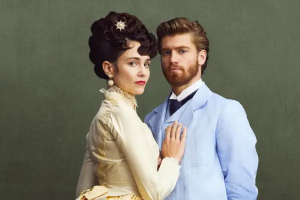 Danny Griffin as Jolyon Forsyte Jr and Tuppence Middleton as Frances Forsyte in The Forsytes, wearing period dress and stood against a green background.