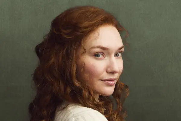 Eleanor Tomlinson as Louisa Byrne in The Forsytes, wearing period dress and stood against a green background.