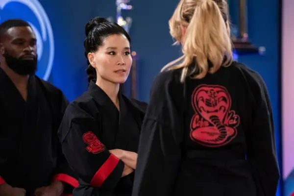 Alicia Hannah-Kim plays Kim Da-Eun in Cobra Kai. In this scene, she stands arm folded in conversation with Tori.