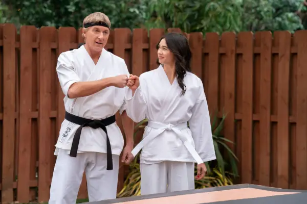 William Zabka as Johnny Lawrence, Oona O’Brien as Devon Lee, fist-bumping in a scene from Cobra Kai