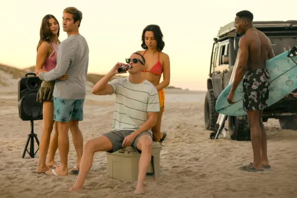 Mia Challis as Ruthie, Austin North as Topper, Drew Starkey as Rafe, Fiona Palomo as Sofia, Deion Smith as Kelce in Outer Banks gathered on a beach