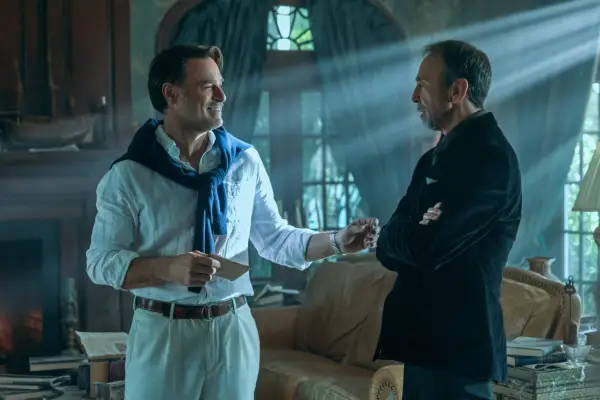 Anthony Crane as Groff and David Jensen as Genrette in Outer Banks having a discussion in a dimly lit mansion living room.