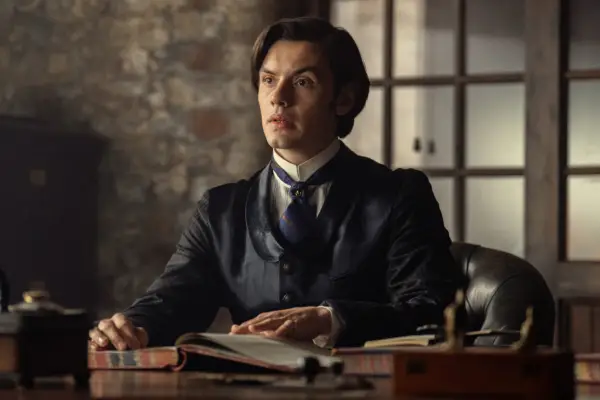 Louis Partridge as Edward Guinness in House of Guinness, sitting at a table with a book open in front of him.