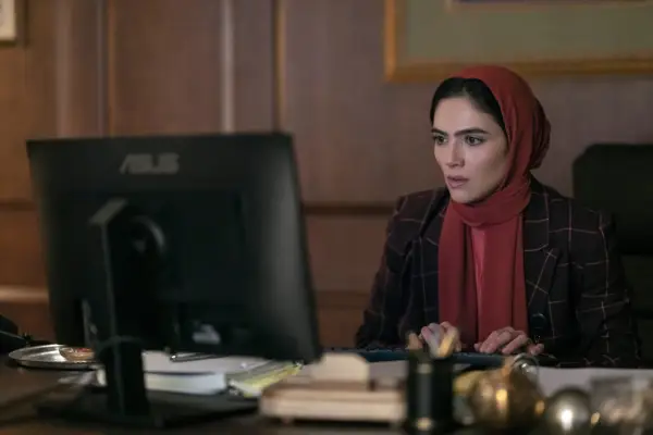 Arienne Mandi as Noor in The Night Agent, sat looking at a computer