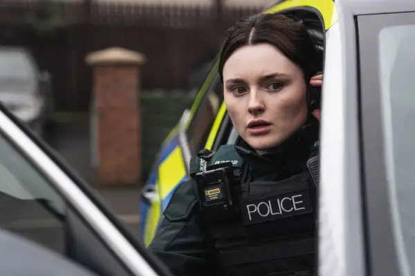 Katherine Devlin as Annie Conlon in Blue Lights season 3, leaning out of her police car and looking worried as she listens to her earpiece.