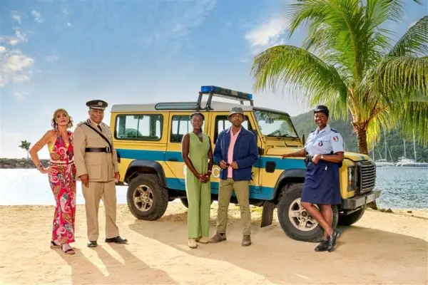 Death in Paradise season 14 cast standing next to a large car