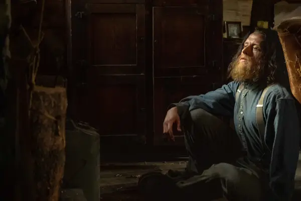 Rory Culkin as Samuel Lafferty, with a big beard and sat on the floor in Under the Banner of Heaven