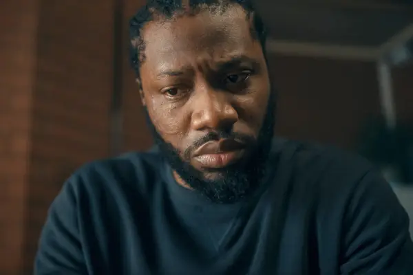 Tom Moutchi looking at the ground sombrely in Criminal Record