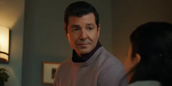 Alex Quijano as Uncle Richard who is looking at Jackie with a slightly smile.